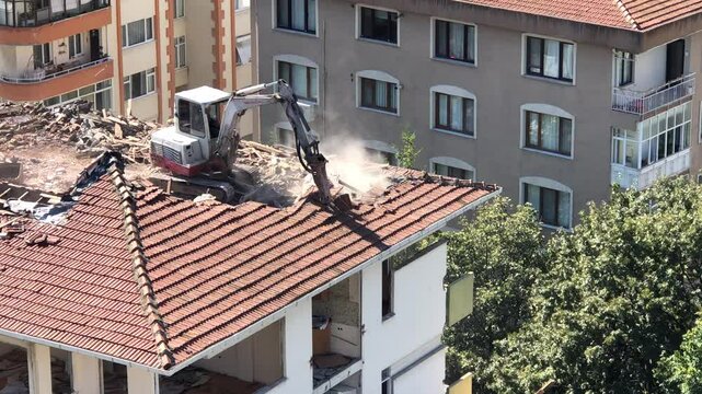 A dilapidated building in Turkish is being demolished - 4K Construction Building - Demolition digger destroying an old building - Demolition of apartment block - Medium shot of house being demolished