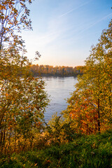 Colorful autumn landscape with birch grove with golden foliage on the shore of the lake and beautiful reflections at sunset. High quality photo