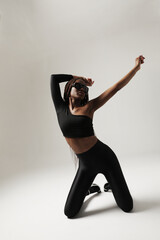 Young gorgeous African American woman with long braids dancing indoor. Vertical.