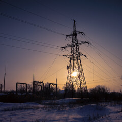 High-voltage power lines during dramatic winter sunset in extremely cold weather. Concept of...