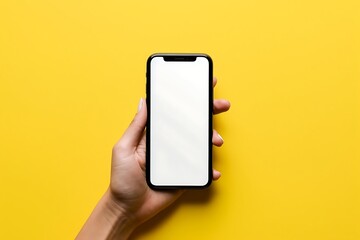 Female hand holding smartphone with blank screen on yellow background, mockup