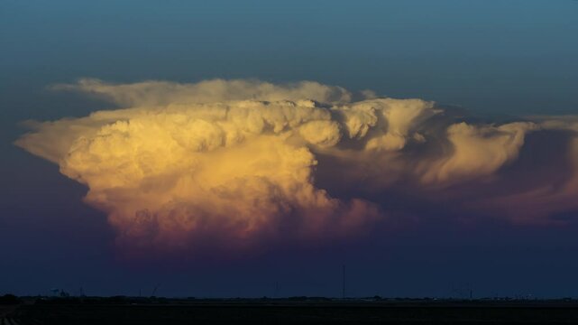 Drifting storm clouds reflect vibrant sun set colors