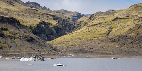 panorama of a green mountain valley with a meltwater lake with icebergs during the summer, Sólheimajökull, South Iceland