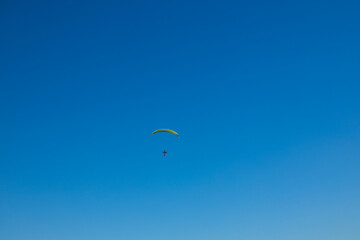 Alone paraglider flying in the blue sky against the background of clouds. Paragliding in the sky on a sunny day. High quality 