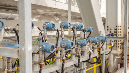 Industrial Equipment Close Up. Close-up of industrial sensors and equipment mounted on a metal platform, showcasing a network of pipes, wires, and cables connecting them. 
