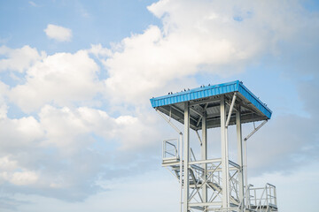 Steel Watchtower in the Sky. A steel tower with a blue roof, positioned against a backdrop of a...
