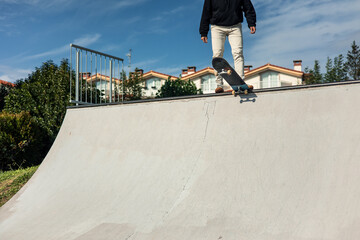 Unrecognizable skater standing on skateboard at edge of half-pipe
