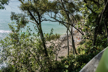People relaxing on the rocks near Little Cove Beach from Park Road walk at Noosa Heads, Queensland, Australia