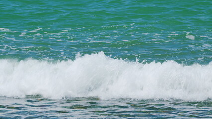 Naklejka premium Sandy Coastline. Backlit Colorful Blue Turquoise Waves. Beautiful Relaxing View On Vacation. Real time.