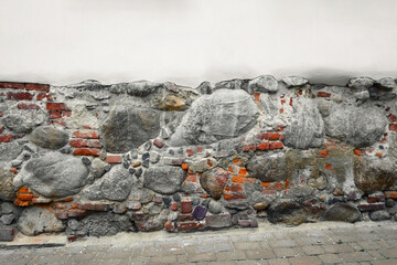 Historic stone wall with assorted bricks and stones in an urban setting during daylight hours