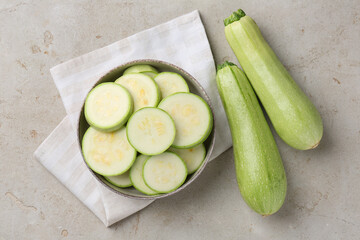 Fresh cut and whole zucchinis on grey textured table, flat lay