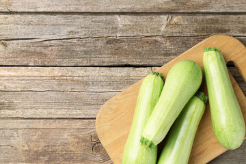 Board with fresh zucchinis on wooden table, top view. Space for text