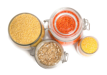Different cereals and lentils in jars isolated on white, top view
