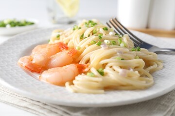 Delicious pasta with shrimps and green onions on table, closeup