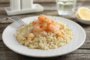 Delicious risotto with shrimps and cheese on wooden table, closeup