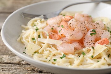 Delicious pasta with shrimps and cheese on wooden table, closeup