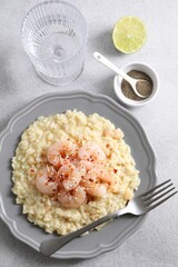 Delicious risotto with shrimps and cheese served on light grey table, top view