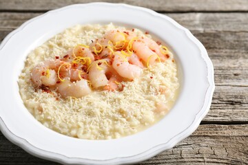 Delicious risotto with shrimps and cheese on wooden table, closeup