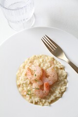 Delicious risotto with shrimps and cheese on white table, above view