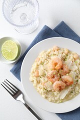 Delicious risotto with shrimps and cheese on white table, top view