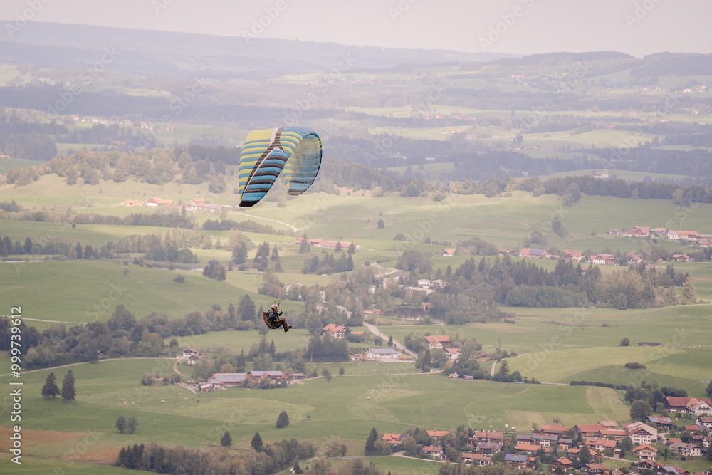 Wall mural a paraglider soars above the green fields and forests of bavaria, with a scenic view of the rural la