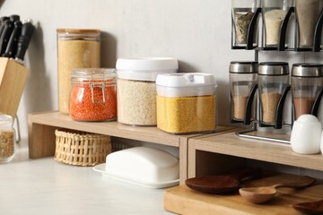 Different types of cereals and legumes in containers on light marble table