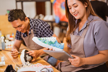 asian female worker holding tablet and painted sneakers