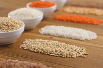 Different types of cereals and legumes on wooden table, closeup