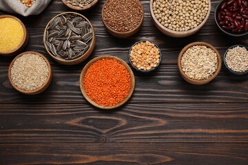Different types of cereals, seeds and legumes on wooden table, flat lay. Space for text