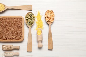 Different types of seeds and cereals on white wooden table, flat lay. Space for text