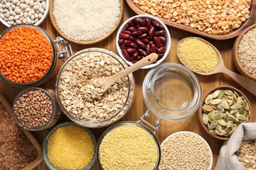 Different types of cereals, legumes and seeds on wooden table, flat lay