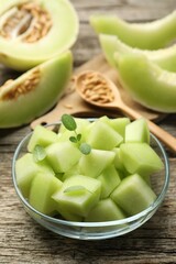 Slices of yummy melon in glass bowl on wooden table, closeup