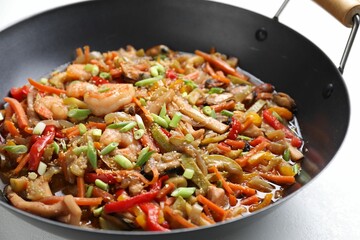 Stir-fry sea food in wok on light table, closeup