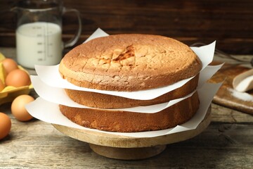 Tasty cut sponge cake and ingredients on wooden table