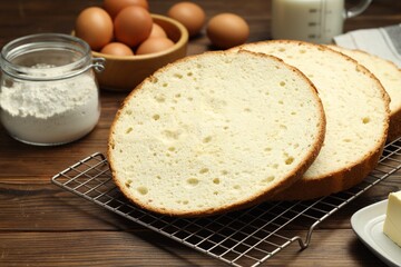 Tasty cut sponge cake and ingredients on wooden table, closeup