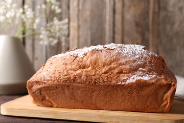 Tasty sponge cake with powdered sugar on wooden table, closeup