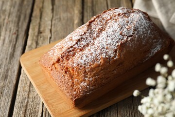 Tasty sponge cake with powdered sugar on wooden table, closeup