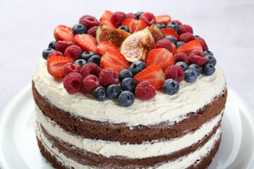 Delicious chocolate sponge cake with berries on light table, closeup