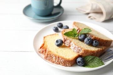Freshly baked sponge cake, mint and blueberries on white wooden table