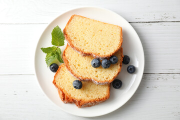 Freshly baked sponge cake, mint and blueberries on white wooden table, top view