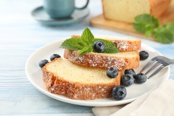 Freshly baked sponge cake, blueberries and mint on light blue wooden table, closeup
