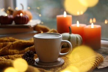 Cup of coffee, cones and soft sweater on table. Autumn atmosphere
