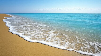 A serene beach scene with soft waves gently lapping at the sandy shore under a clear blue sky.