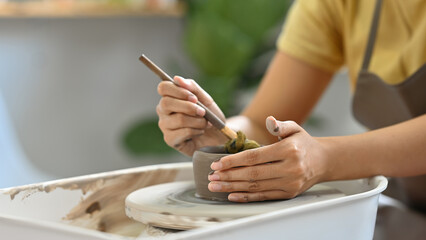 A close-up of hands skillfully molding clay on a pottery wheel, capturing the focus and creativity involved in the art of crafting handmade pottery.