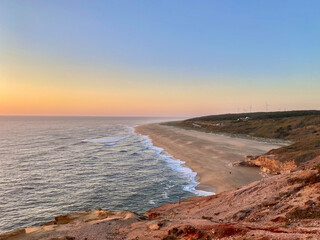 Beautiful sunset on the ocean in the surfing capital of Nazare, Portugal. View of the wind turbines