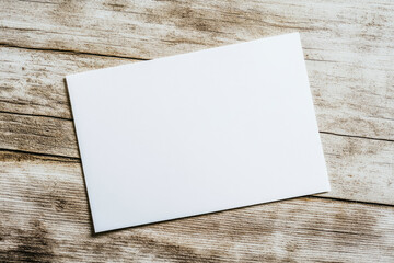 A 5x7 inch white card, placed on a wooden table, in a mockup style, viewed from above. Created with Ai