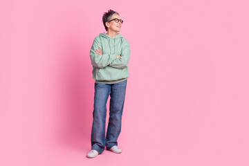 Fototapeta premium Full length photo of funny good mood lady wear khaki hoodie arms folded looking empty space isolated pink color background