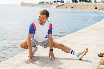 Man Stretching Along Waterfront During Daytime Workout in a Scenic Outdoor Setting
