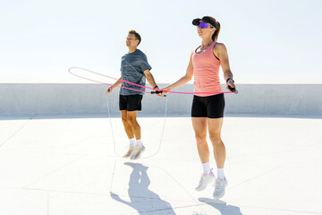 Couple Skipping Rope Together Outdoors on a Bright, Sunny Day, Showcasing Fitness and Teamwork in...