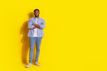 Fototapeta premium Full length photo of cheerful positive guy dressed checkered shirt hands crossed emtpy space isolated yellow color background